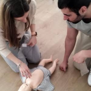 Padres practicando con muñeco en el Curso Online Primeros Auxilios Bebés y Niños