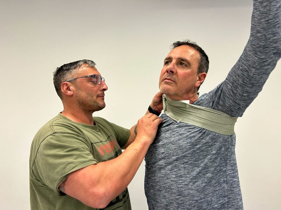 Instructor colocando un vendaje de control de hemorragia a un alumno