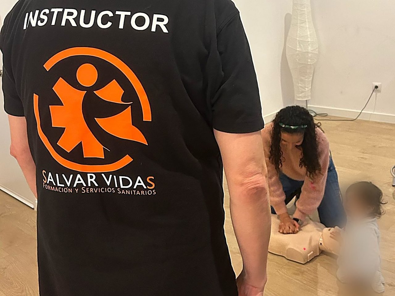Instructor de Salvar Vidas y alumna practicando RCP en un bebe sobre maniqui en un curso de primeros auxilios infantiles