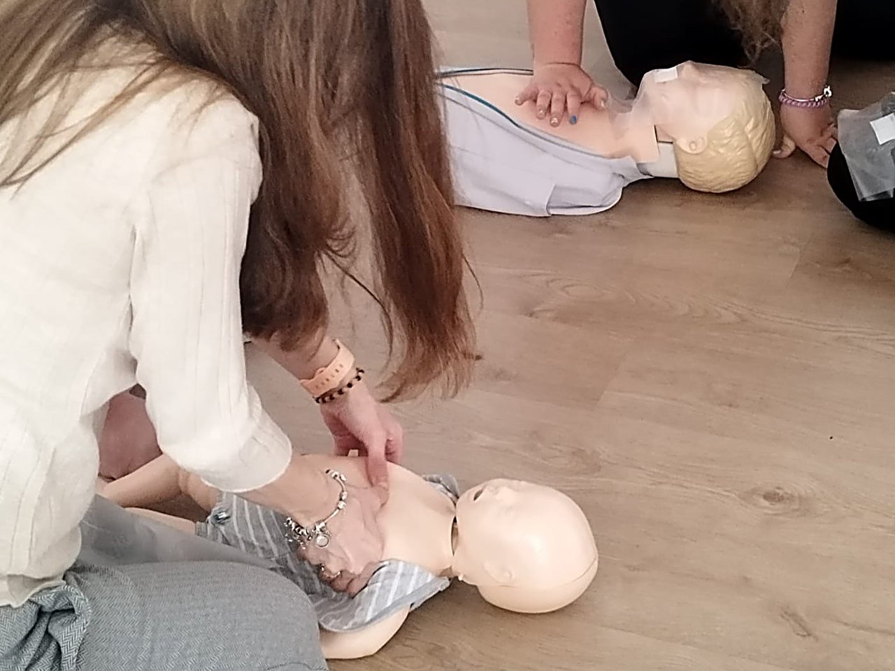 Alumnas practicando RCP con compresiones toracicas sobre maniquies de nino y bebe en un curso de Salvar Vidas