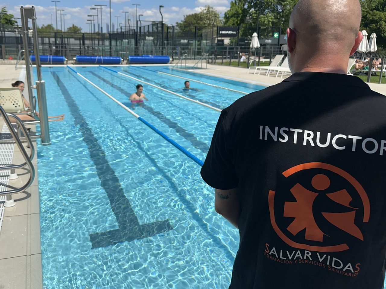Instructor de socorrismo acuatico de Salvar Vidas supervisando a alumnos que practican en la piscina