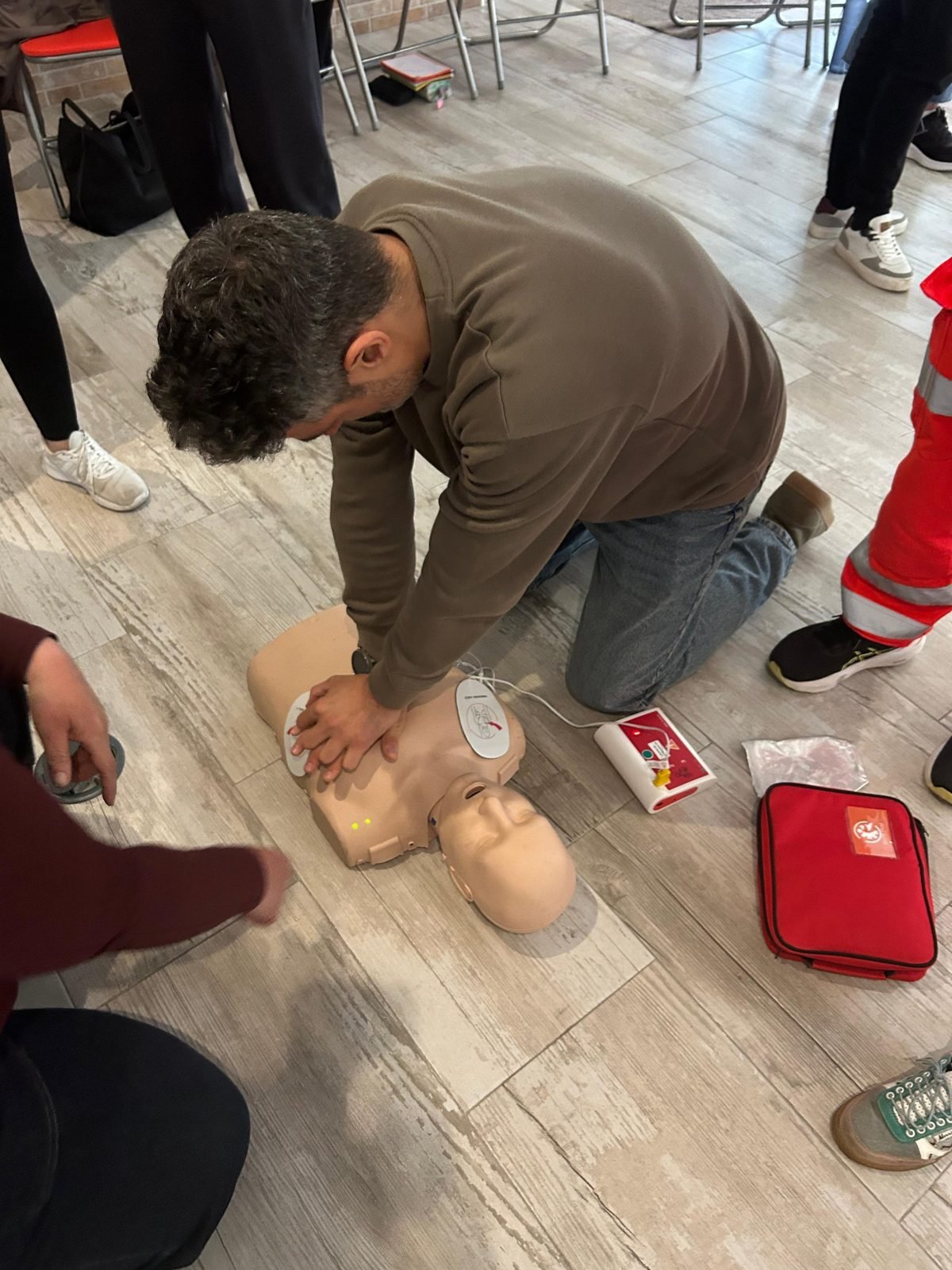Alumno practicando compresiones torácicas con el desfibrilador de entrenamiento conectado al maniquí